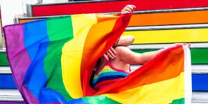 Gay pride - Couple derrière un drapeau arc-en-ciel